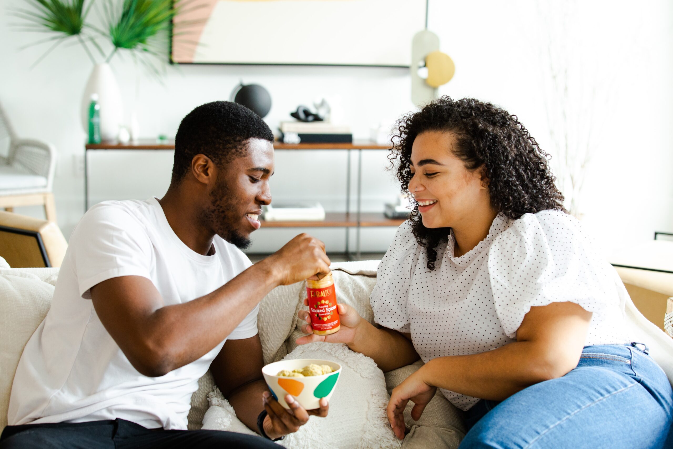 A couple shares a snack while smiling at one another. This could represent closer bonds by working with an online therapist in Brooklyn, NY. Learn more about building self-esteem in Brooklyn, NY and other services today.