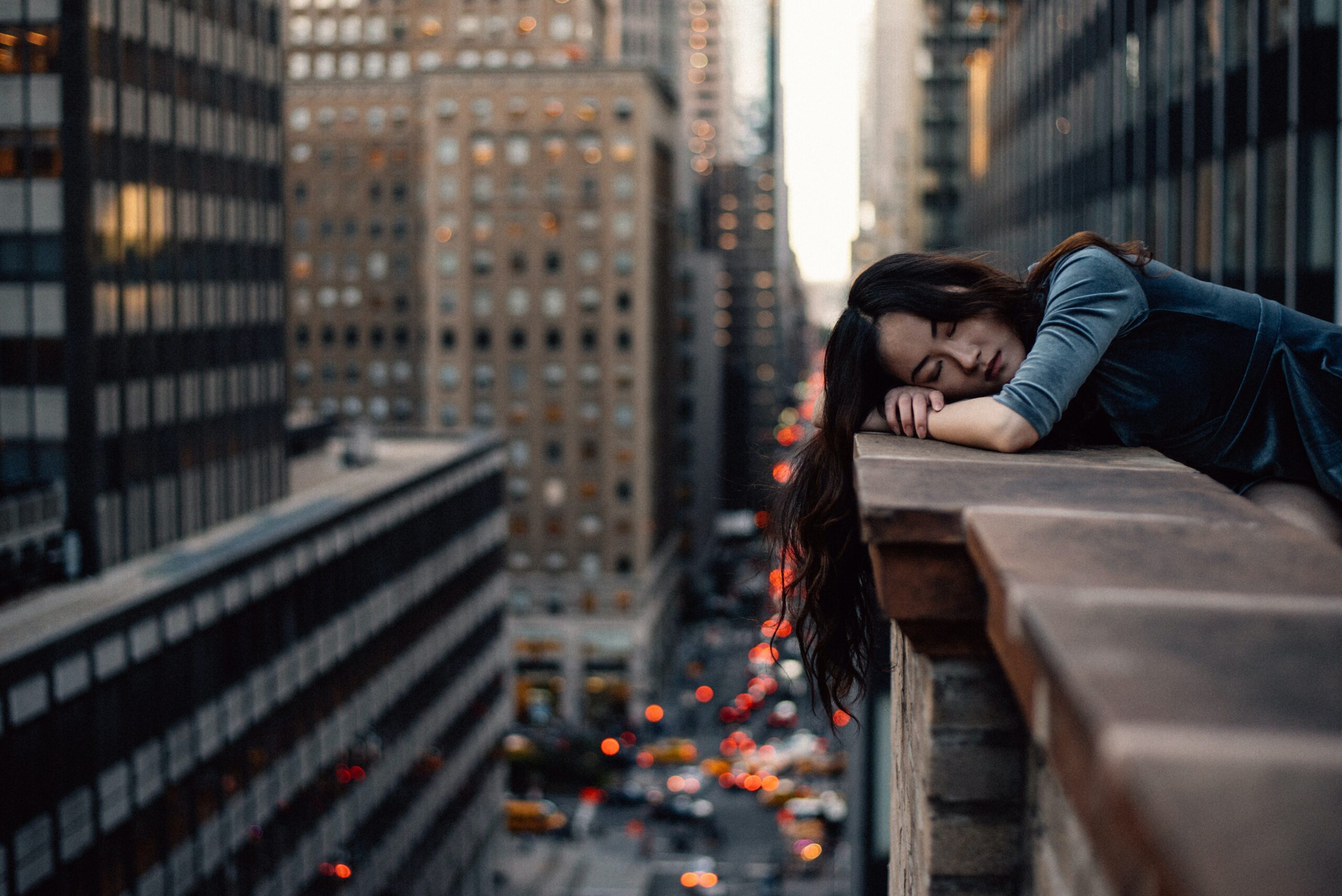 A woman rests her head on a ledge while listening to the city sounds. Learn more about the help that therapy in Brooklyn, NY can offer by searching for individual therapy in Brooklyn, NY. Contact a black therapist in Brooklyn, NY for support.
