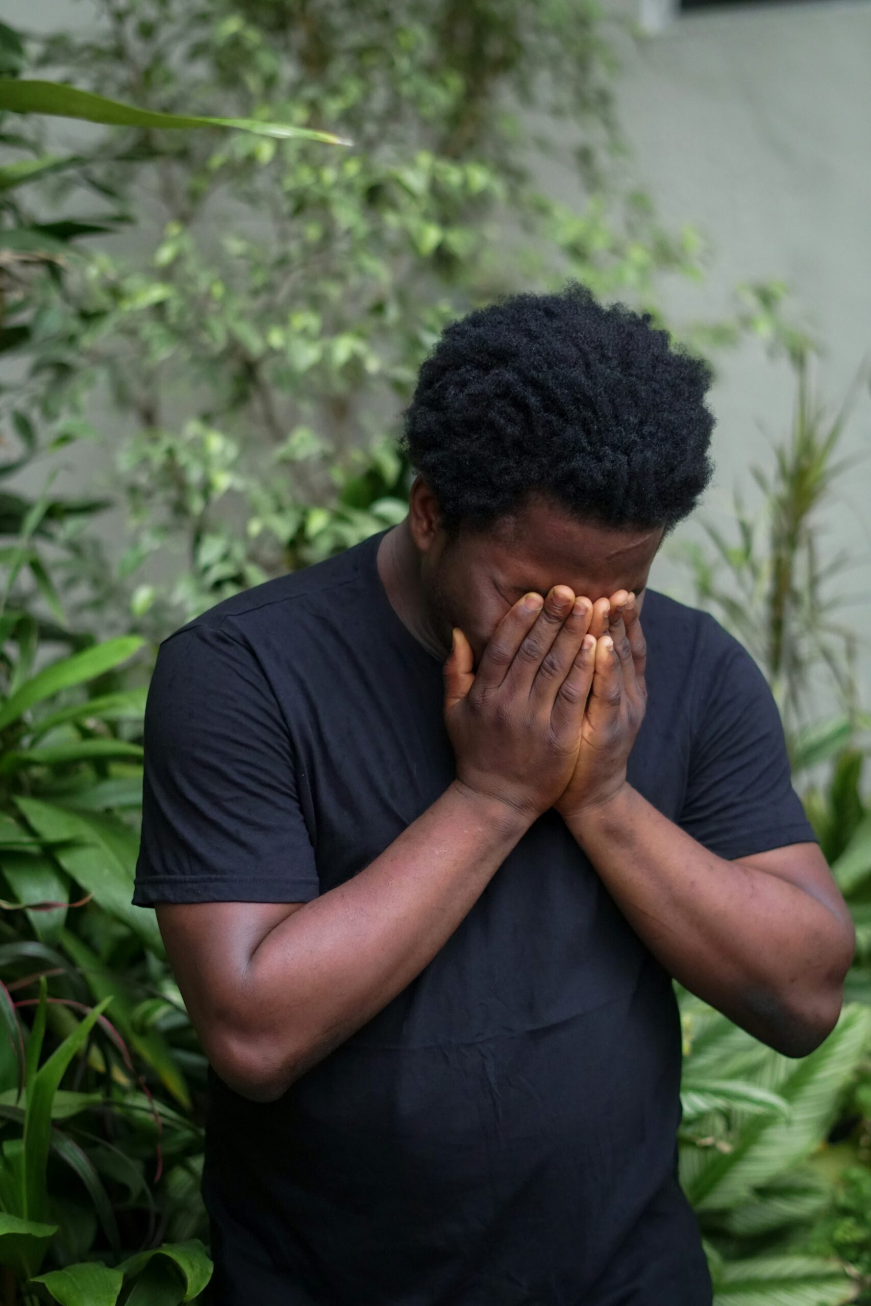 A Black man in distress with hands covering his face, conveying the weight of anxiety symptoms in Brooklyn, NY and the healing support available through a Black therapist in Brooklyn, NY offering therapy for anxiety.