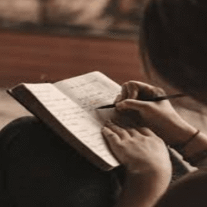 A person writes in a journal in warm light, reflecting the emotional processing practices a BIPOC anxiety therapist in Brooklyn, NY and a culturally sensitive therapist in Brooklyn, NY at SG Wellness encourages.