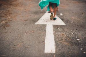 A person's feet step forward along a large white arrow painted on the pavement, capturing how one small step builds momentum. For anyone tired of standing still, a young adult therapist in Brooklyn, NY can help. An attachment therapist in Brooklyn, NY, including a BIPOC therapist in Brooklyn, NY, can walk that path alongside you. 